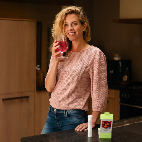 Eine Frau hält ein Glas mit dem NutraLinea Apfelessig-Getränk in der Hand – ein erfrischendes, kalorienarmes Getränk mit nur 10 kcal und natürlicher Unterstützung für den Stoffwechsel.