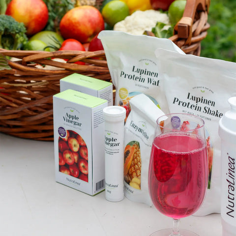Nutralinea-Produkte neben frischem Obst und Gemüse – die Vitamine und Mineralstoffe erinnern an das, was unser Körper aus natürlichen Lebensmitteln kennt und gut aufnehmen kann.